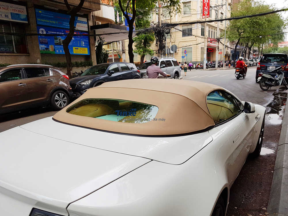 Đối lập với bộ áo trắng, chiếc xe sang mui trần Aston Martin V8 Vantage Roadster có phần mui vải màu be bắt mắt.
