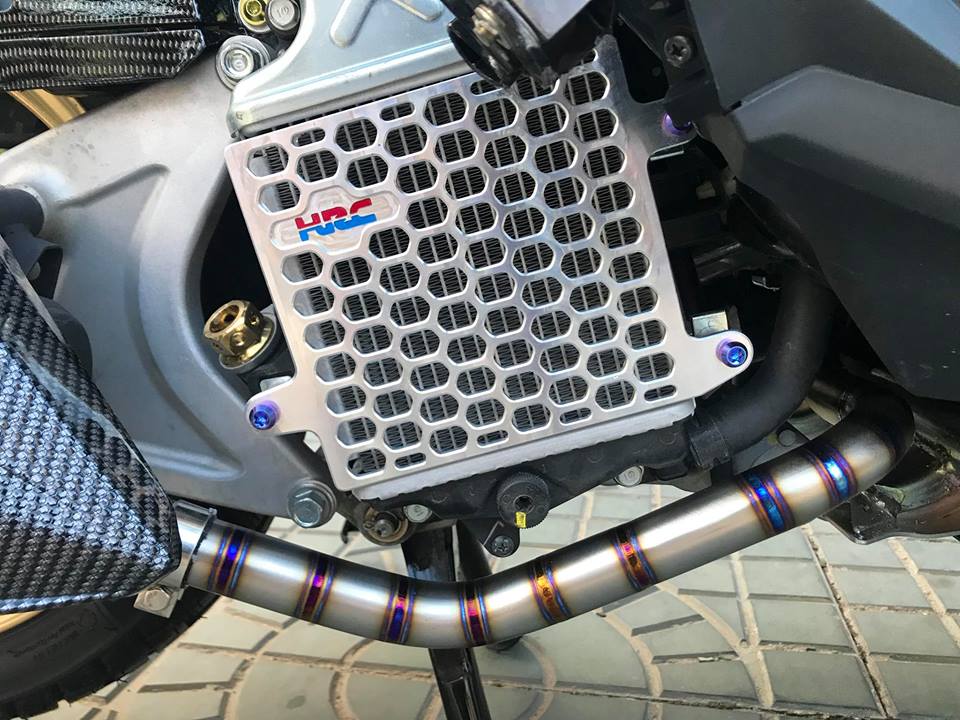 Sang bên hông phải của xe, chiếc Vario 150 độ được chủ nhân đầu tư cho bộ cổ xả titan với các đường hàn tinh tế, bắt mắt và rất nổi bật. Thêm vào đó là ốp nhôm bảo vệ két làm mát tiện dụng.