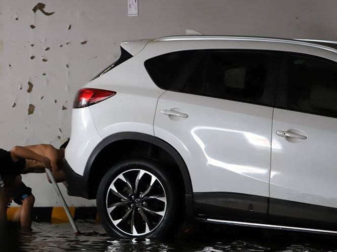 Một chiếc xe được lau chùi bùn đất sáng quang, chờ xe cứu hộ đến kéo đi