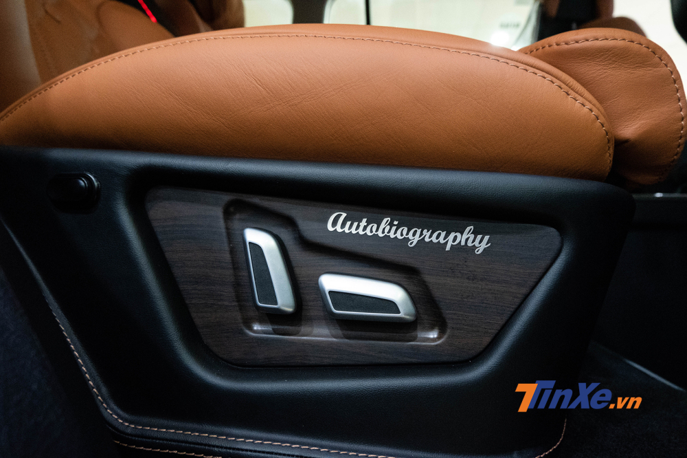 Khu vực điều chỉnh độ ngả của hàng ghế 2 có nền gỗ, viền phím mạ crôm và dòng chữ “autobiography” uốn lượn