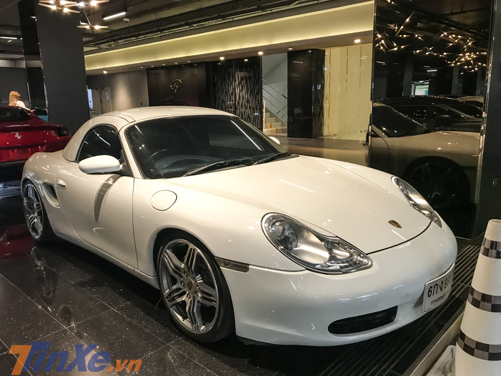 Một chiếc xe thể thao Porsche Boxster S đời cũ và lấp ló phía sau là siêu xe Ferrari Portofino