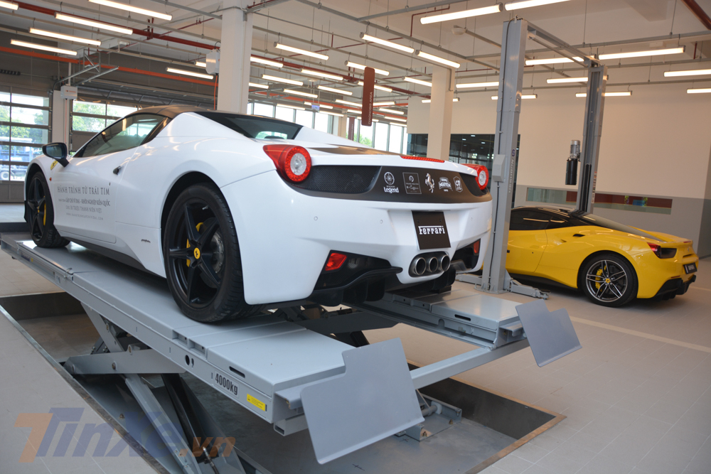 Chiếc siêu xe Ferrari 458 Spider màu trắng được cho nằm trên cầu nâng, riêng chiếc siêu xe Ferrari 488 GTB màu vàng đầu phía dưới