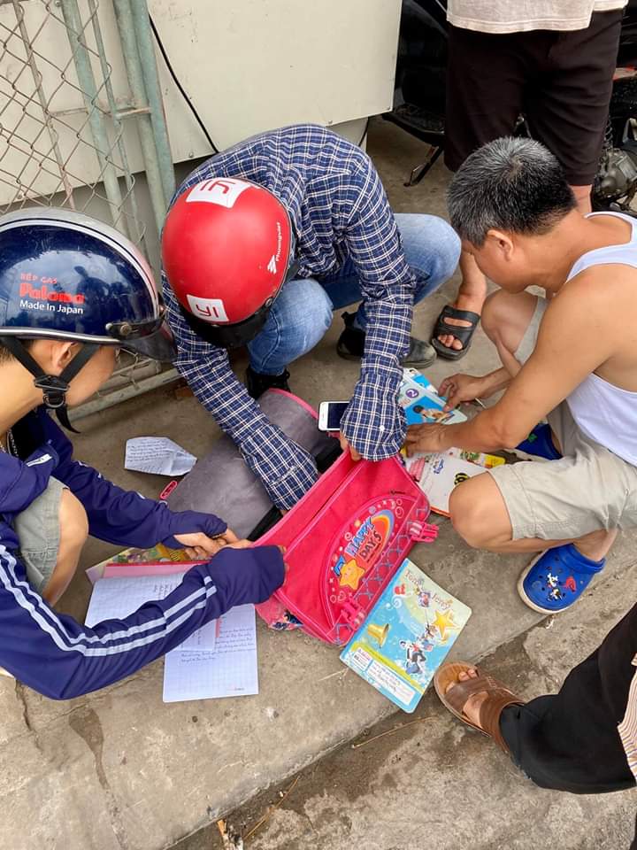 Người dân xem tập vở của em học sinh gặp nạn để thông báo người thân đến bệnh viện Người dân xem tập vở của em học sinh gặp nạn để thông báo người thân đến bệnh viện