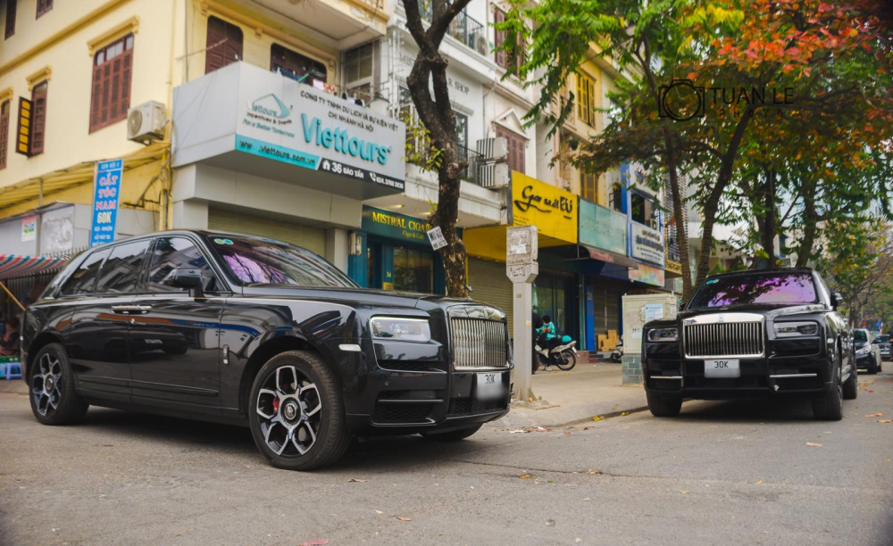 Two super luxury Rolls-Royce Cullinan SUVs, the closest car to the screen is the Black Badge version