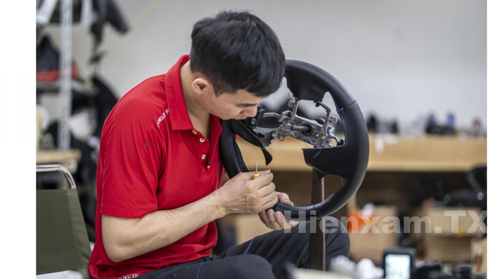 The technician hand sews the new leather covering the steering wheel. Before sewing, a thin layer of glue will be applied to create adhesion with the old layer of leather on the steering wheel.